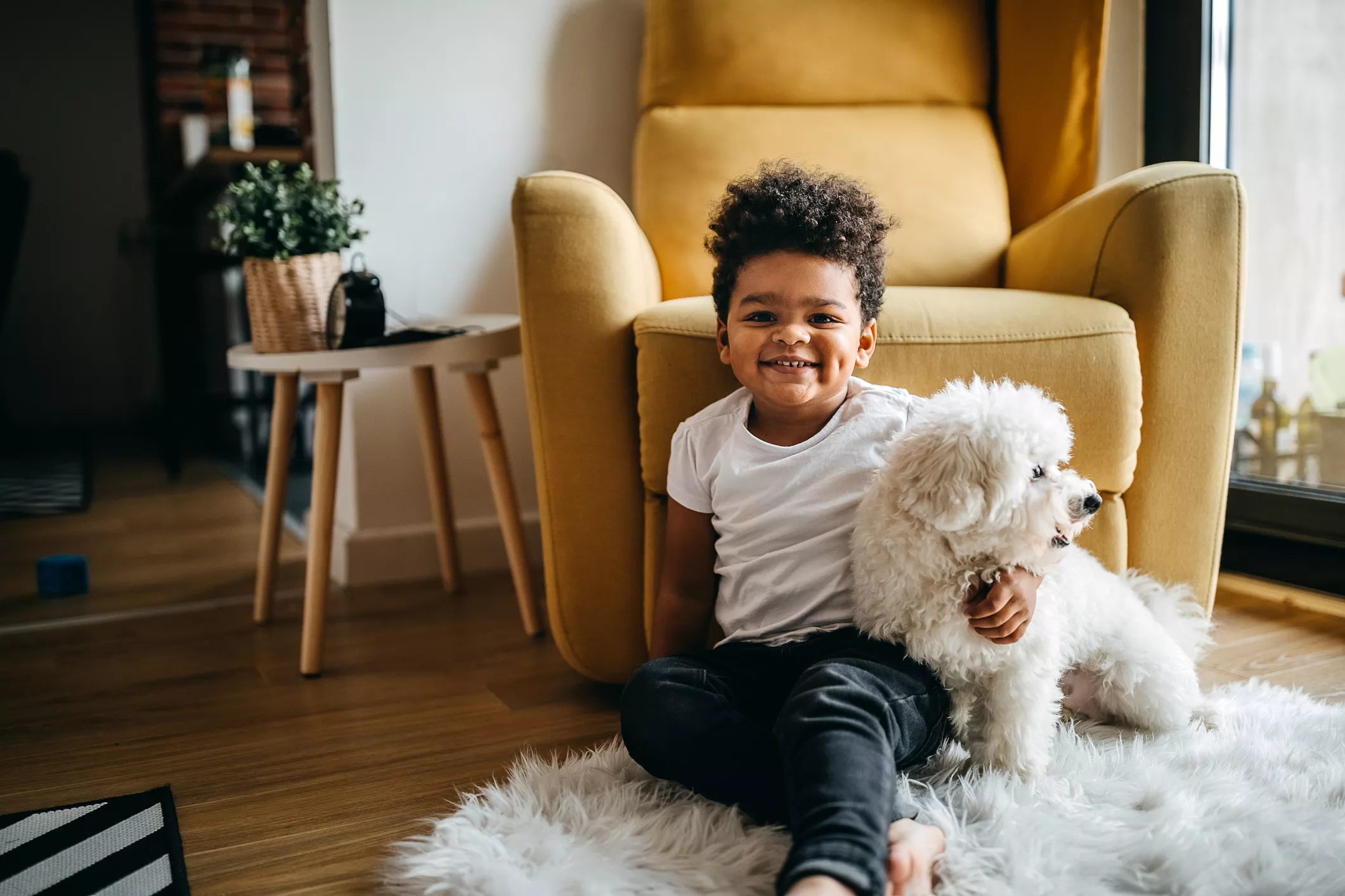 Child sits on the floor with a white dog